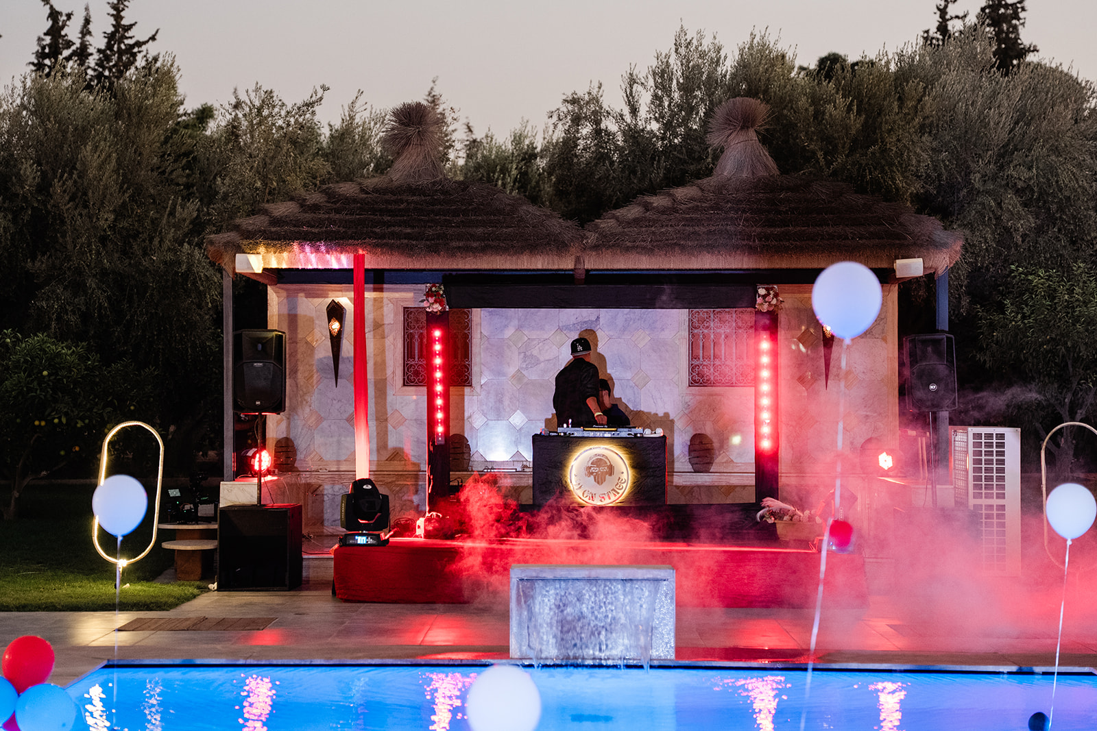 Ambiance nocturne au bord de la piscine avec tables dressées et jeux de lumière